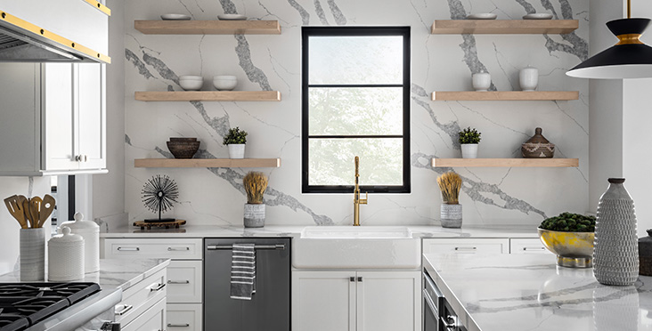 An accent wall of Q Premium Natural Quartz with floating natural wood shelves, farmhouse-style sink, and matching countertop.