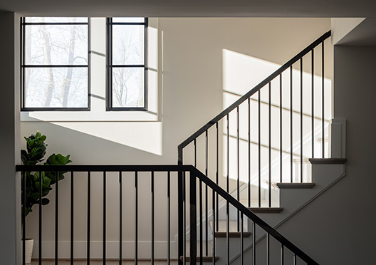 An artfully framed photo of modern iron stair rails and dark framed windows.