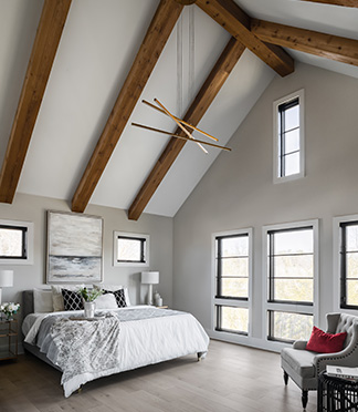 A vaulted ceiling with exposed stained beams, contemporary chandelier, and floor height windows.