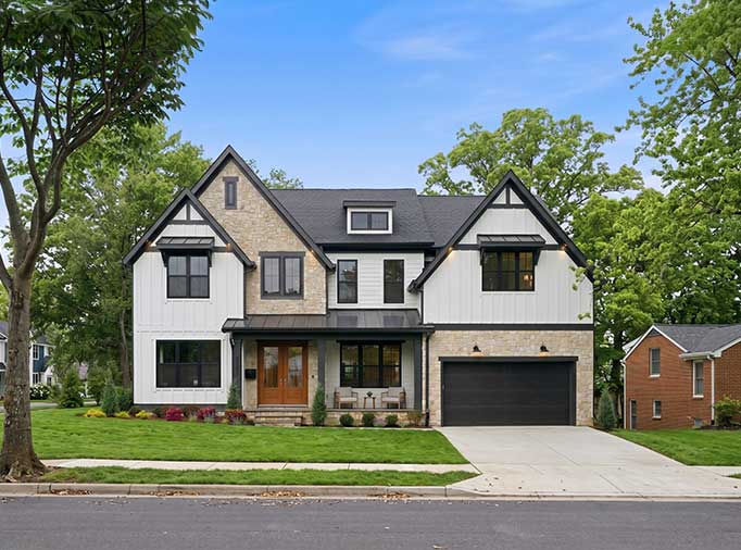 A modern two-story home with white board-and-batten siding, light stone accents, and black-trimmed windows.