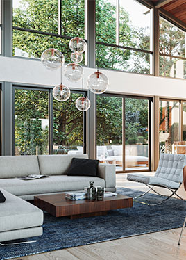 Image shows family room furniture in foreground with wall of tall custom windows and sloping ceiling behind