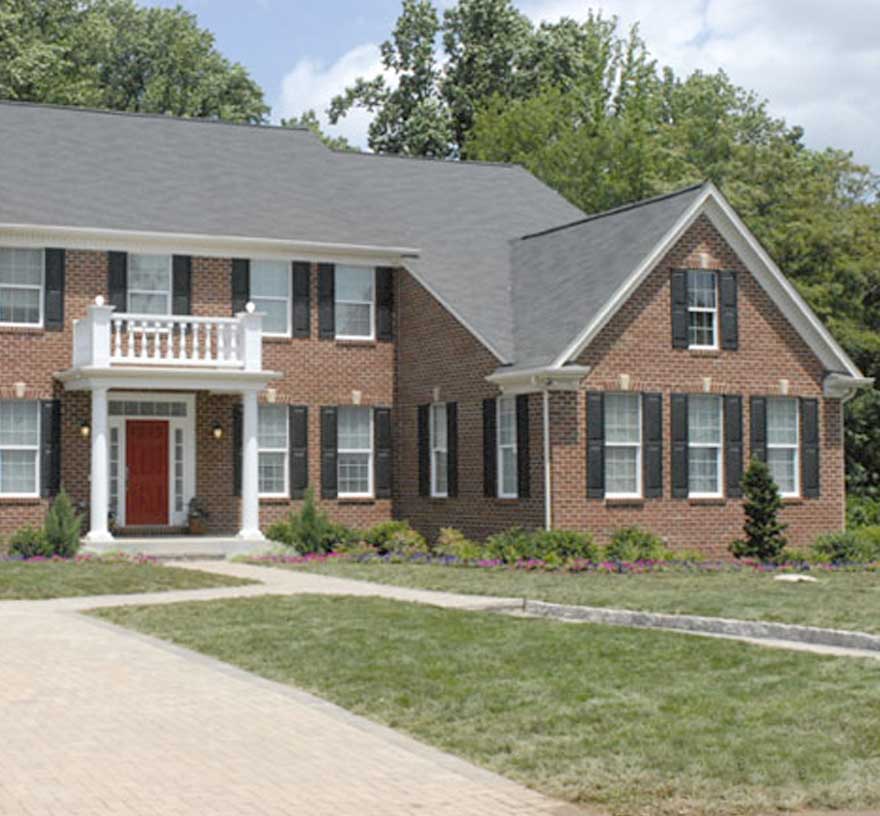 a brick home with portico painted white, red door and dark shutters