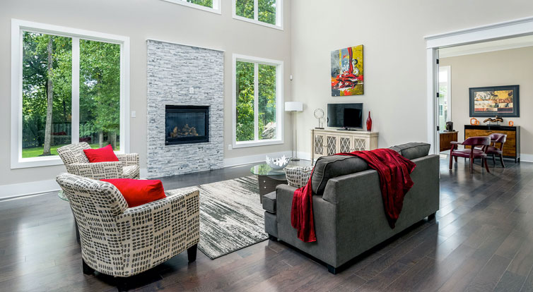 A two story family room featuring a raised gas fireplace with marble surround, and row of three double windows above.