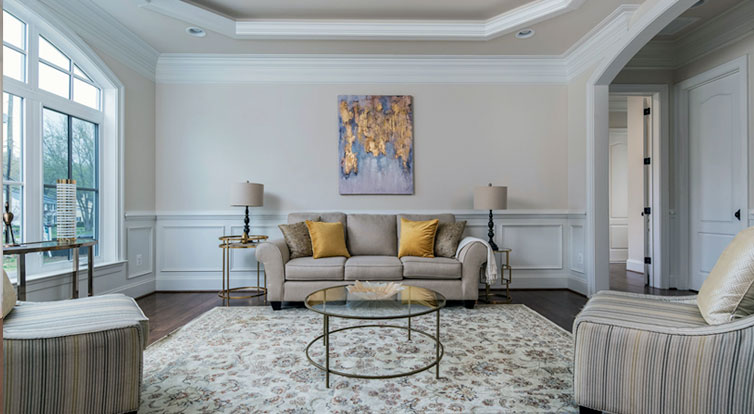 A luxury style living room with deep trimmed tray ceiling, shadow boxes, crown molding, and arched cased opening.