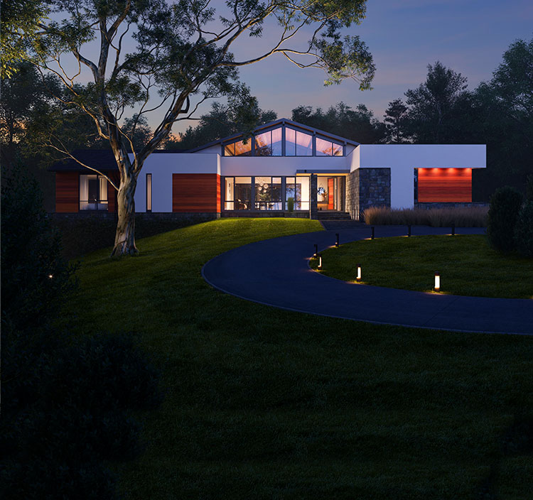 An image of California Modern style custom home illuminated against the night sky, situated in a heavily wooded setting.
