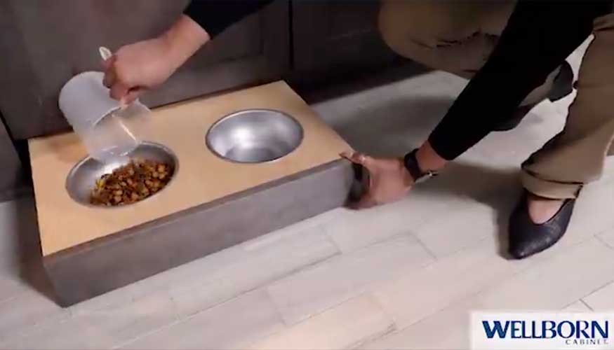 An image showing a hidden pet dish extending from kitchen cabinetry, vendor logo Wellborn Cabinet in corner