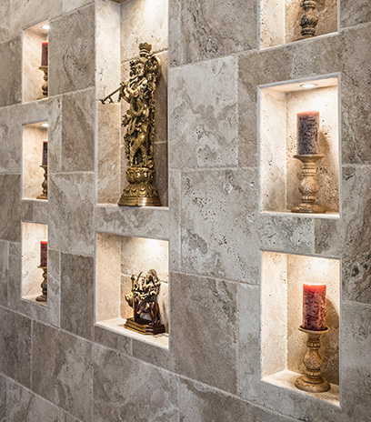 An elegant tiled wall with various carefully arranged niche cutouts to displaying statues and candles.