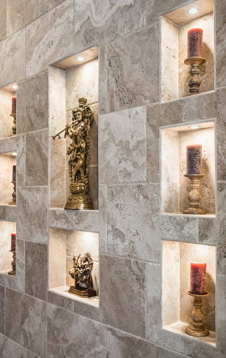 An elegant tiled wall with various carefully arranged niche cutouts to displaying statues and candles.