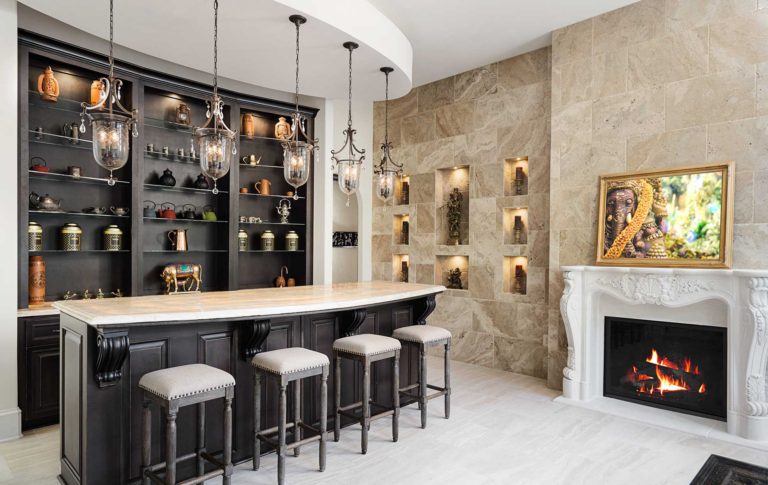 A Tea Lounge, complete with bar/counter, wine cooler and ample seating and space. A tile wall with custom illuminated niches and elaborate fireplace surround.