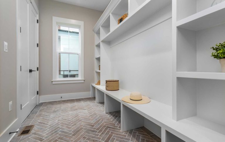 A modern farmhouse style mudroom with shiplap siding accent wall, built in shelving, benches and cubbies.
