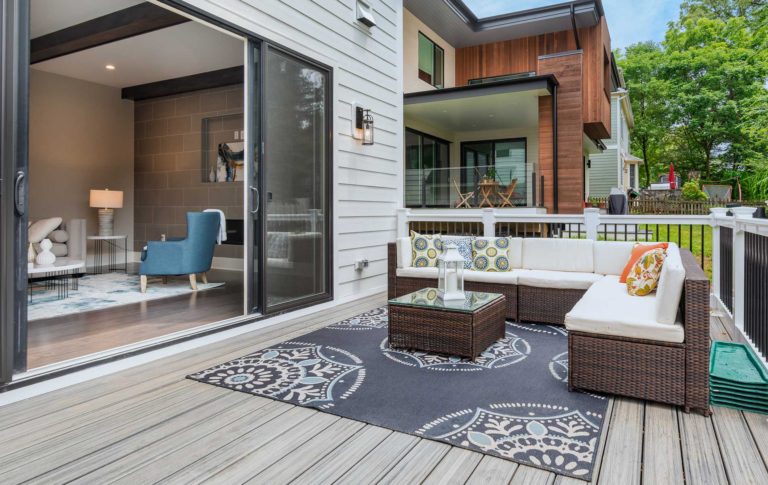 A photo of the Wilmett model Family Room open wide via accordion patio doors to a deck with furniture, white posts and black iron rails.