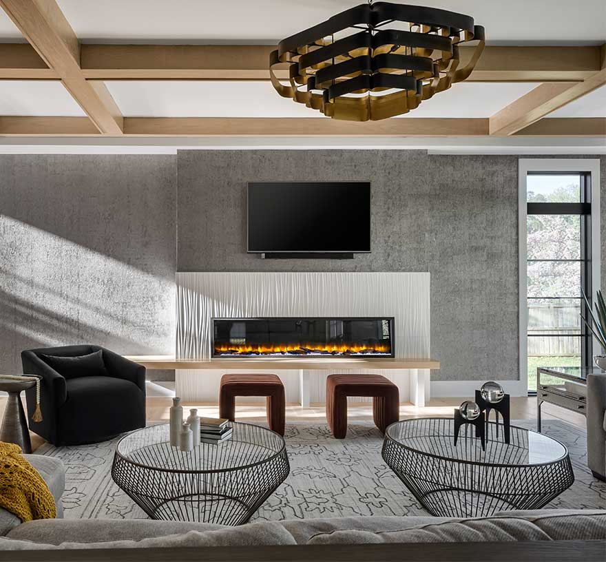 A wide photo showing a family room with 80” linear fireplace with custom surround white textured tile, white ceiling with natural wood beam coffered ceiling.