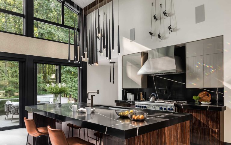 A gourmet Kitchen with contemporary lighting, commercial depth range, frameless cabinets and Silestone® Eternal Noir countertops and backsplash.