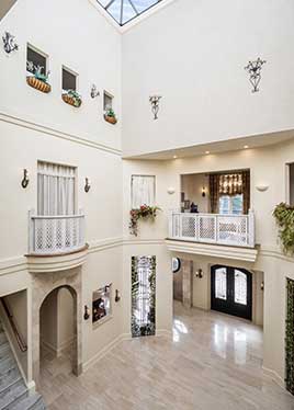 A three story atrium with second floor hallway overlook, romeo and juliet balconies, arched doorways and glass ceiling.