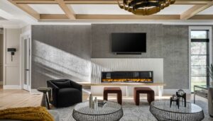 A family room with 80” linear fireplace with custom surround of Porcelanosa® Oxo Line Blanco tile, white ceiling with natural wood beam coffered ceiling.
