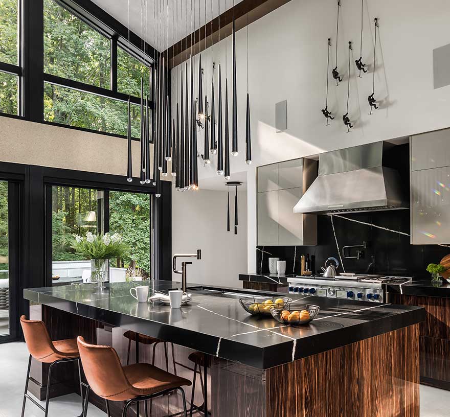 A gourmet Kitchen with contemporary lighting, commercial depth range, frameless cabinets and Silestone Eternal Noir countertops and backsplash.