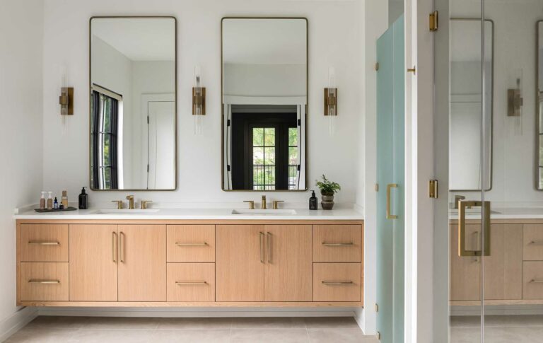 A modern farmhouse owner's bath with dual floating vanity, bedroom windows visible in the mirror.