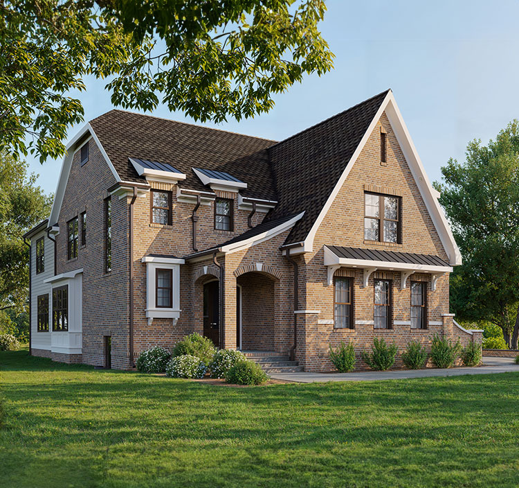 An english cottage style home in red brick on a flat landscape with a few trees, green lawn and landscaping on a sunny day, blue sky.