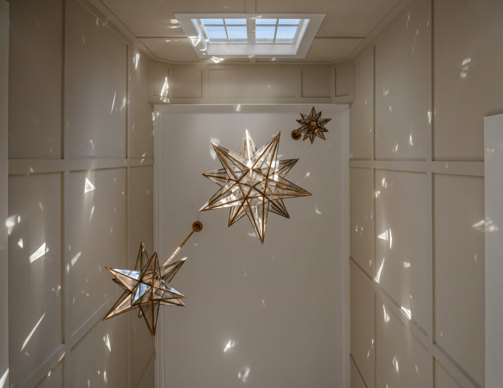 Looking upward in a two story foyer at dangling star shaped chandelier light fixtures