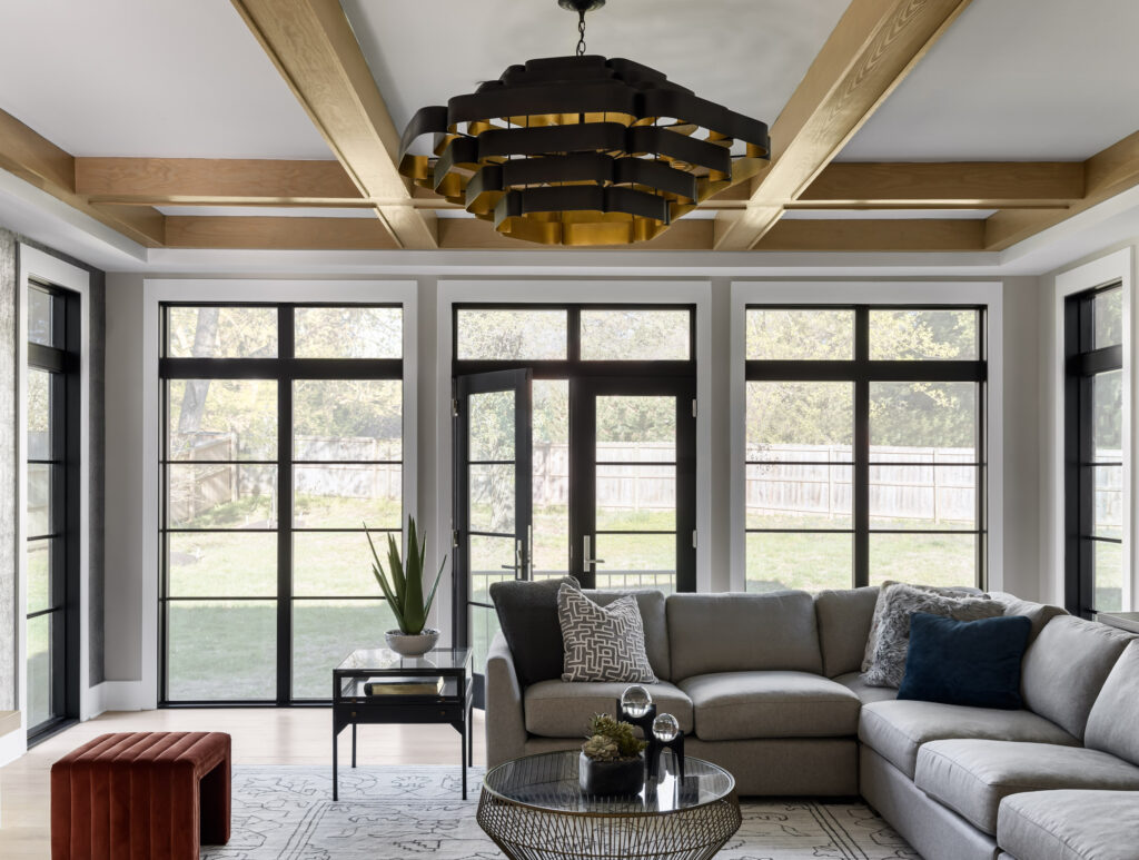 Look from the Family Room through a wall of windows and glass doors into the backyard, couch in the foreground.