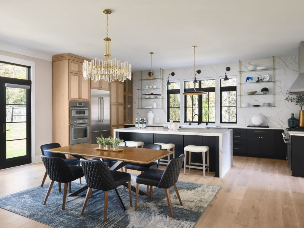 Looking into the Kitchen from behind the Breakfast area, table and chairs in the foreground, modern quartz walled Kitchen behind.