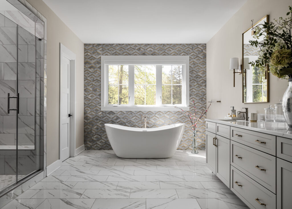 A free standing tub against tiled accent wall, shower and vanity to either side in the foreground