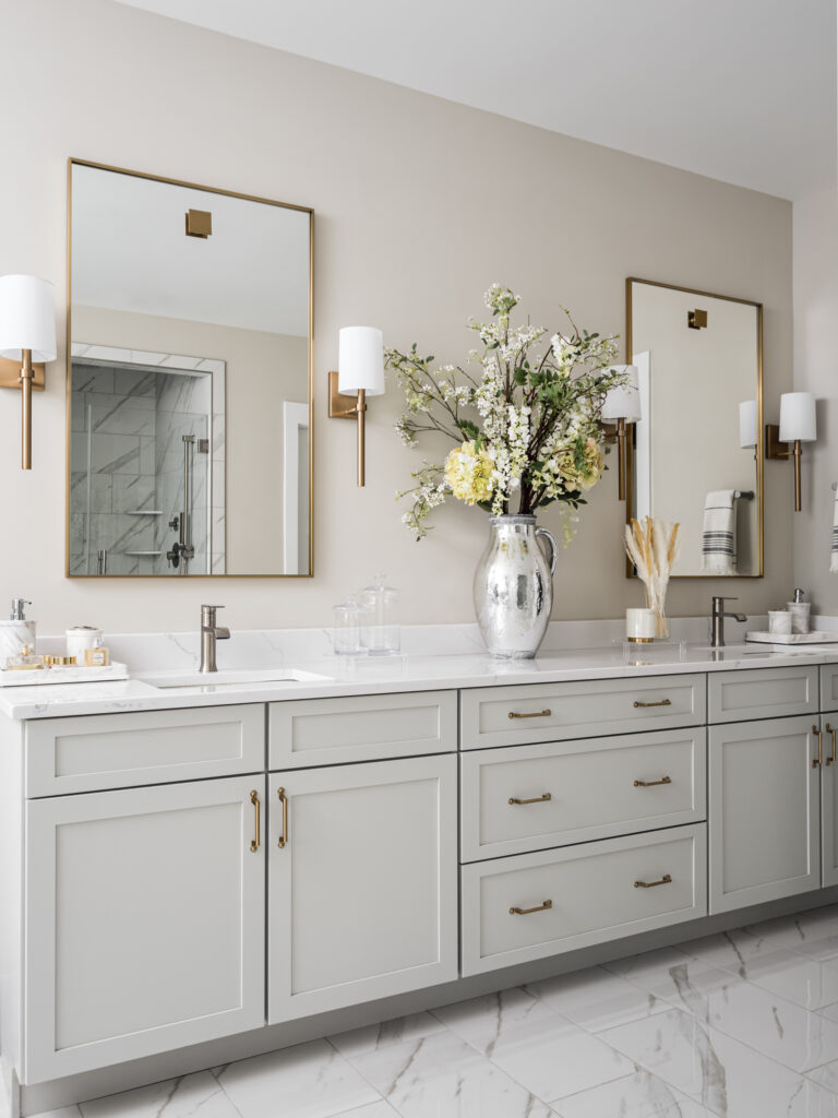 Owner's bath with dual sink vanity and flower arrangement on the counter. Shower visible in the mirror.