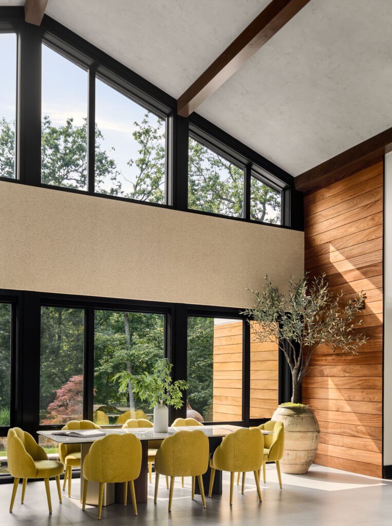 Looking out the front of the home from the Dining Room, table in the foreground, to the right a paneled wood accent wall matches the wall outside.