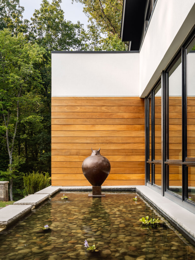 A reflecting pool and statue in front of the home, adjacent to the Dining Room behind the windows.