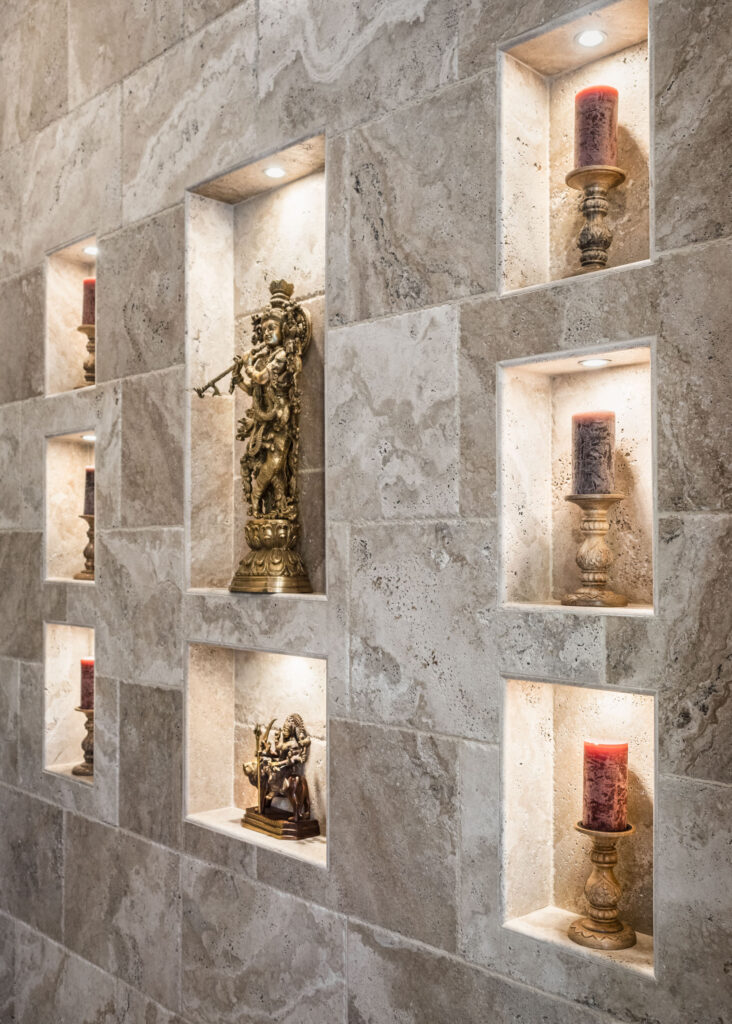 An elegant tiled wall with various carefully arranged niche cutouts to displaying statues and candles.
