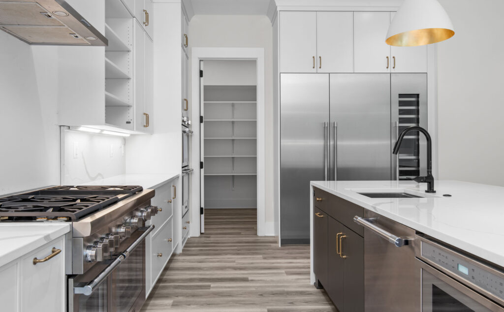 A contemporary kitchen with oversized cabinet depth refrigerator, freezer and wine fridges, range to the left in the foreground, dishwasher and microwave drawer to the right.