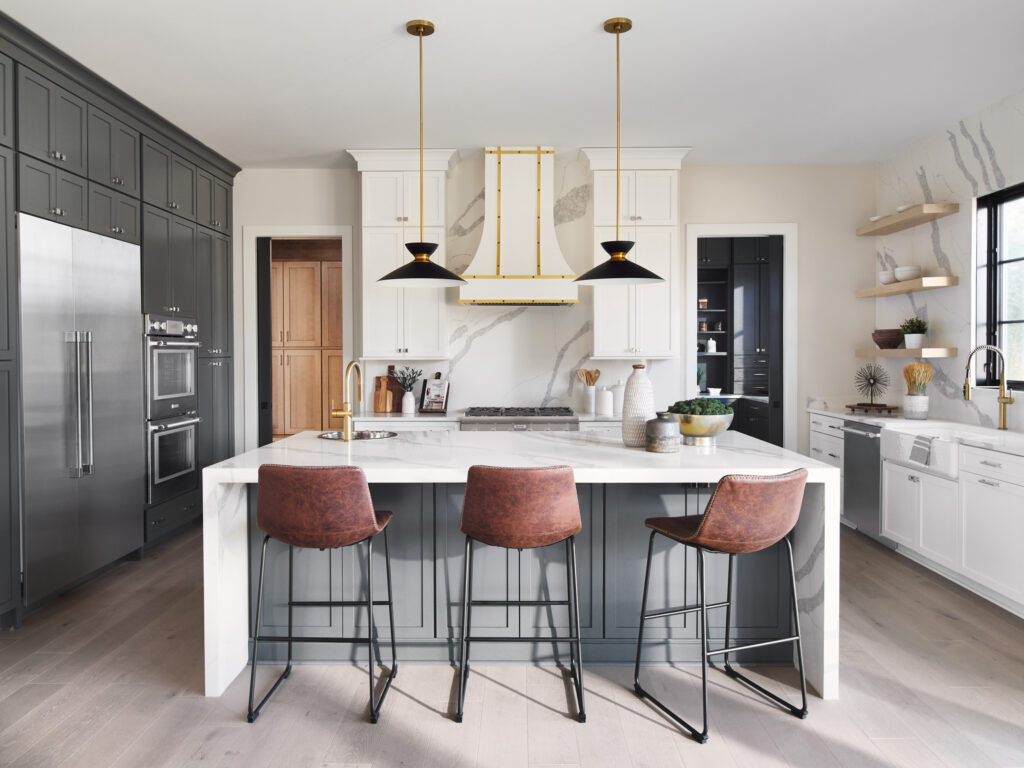 A modern farmhouse kitchen with quartz waterfall island, quartz accent walls, white cabinets and white fume hood.