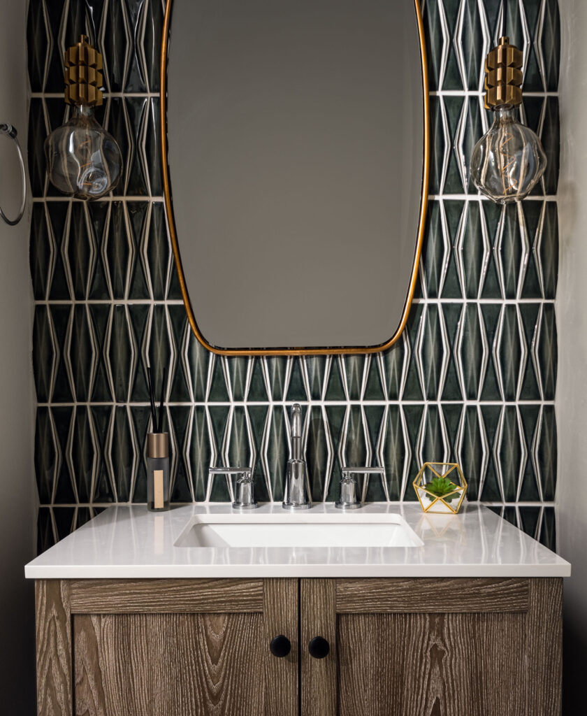 A Powder Room vanity with white top, tile accent wall in textured green tile with deep white lined patterns