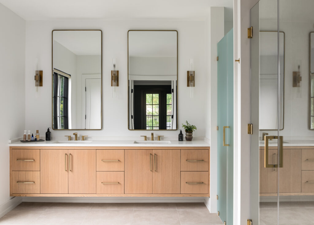 A modern farmhouse owner's bath with dual floating vanity, bedroom windows visible in the mirror.