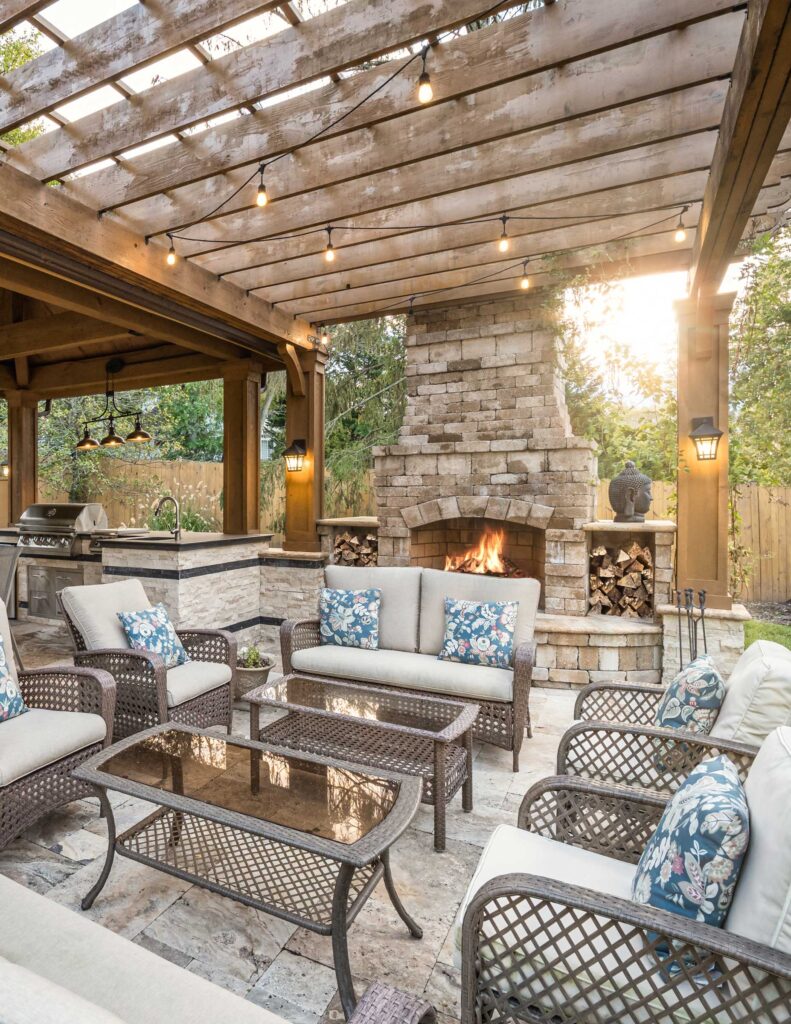 A patio with built-in fireplace, beige furniture and built-in grill and sink for a complete outdoor kitchen