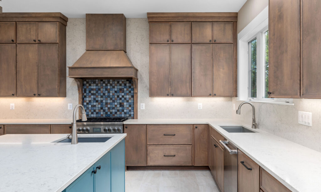 Kitchen sink area with white quartz countertops, medium-tone wood cabinetry, a stainless steel dishwasher, and a window looking out to the yard.